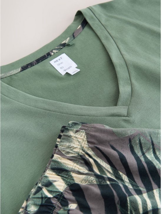 Detail van de hals van een groen V-hals T-shirt met een short met bladerenprint.