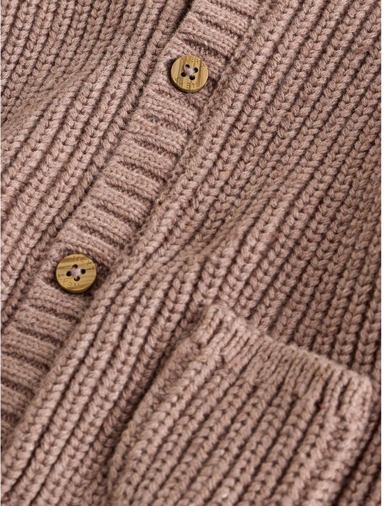 Sluiting van een bruin gebreid babyvest met houten knopen en twee opgestikte zakken.