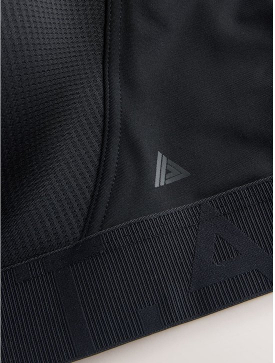 Close-up van zwart sportbeha-detail met driehoekig logo en gestructureerde onderband.