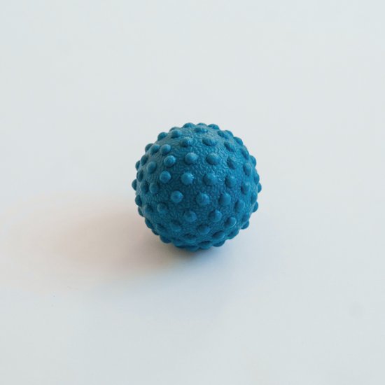 Blauwe, stekelige massagebal op een witte achtergrond.
