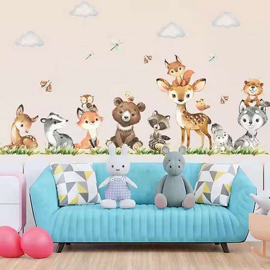 Un sticker mural d'animaux de la forêt, y compris un renard, un ours, un cerf, un raton laveur, un loup et un écureuil, sur un fond rose au-dessus d'un canapé bleu.