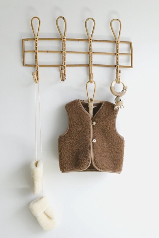 Bruin wollen kinder vest met bruine biezen en twee knopen, hangend aan een kapstok.