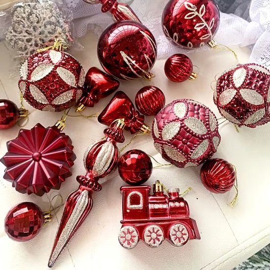 Een verzameling bordeauxrode kerstballen in diverse vormen, waaronder ballen, strikken en een treintje.