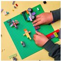 Kinderhanden bouwen met kleurrijke LEGO stenen op groene bouwplaat, met diverse modellen.