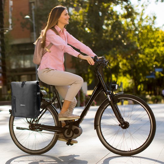 Vrouw met roze blouse op fiets met zwarte Vebics fietstas rugzak.