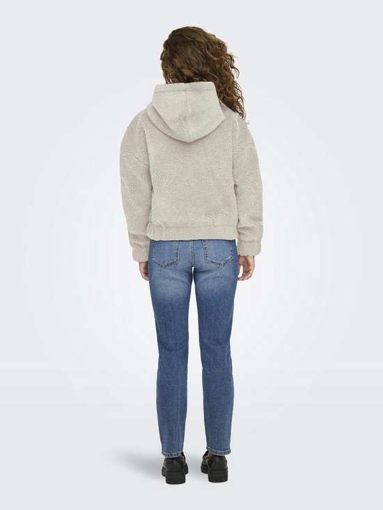 Model van achteren gezien in crèmekleurige teddy jas met capuchon, gecombineerd met spijkerbroek.