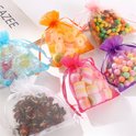 Een groep kleurrijke organzazakjes gevuld met verschillende soorten snoepjes, zoals marshmallows, pepermuntjes en fruitgum.