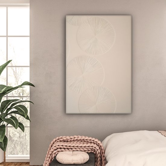 Beige canvas met drie reliëf cirkels, hangend boven een bed in een slaapkamer.