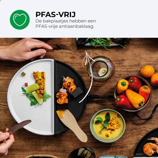 Een gourmetstel op een houten tafel met gegrilde kip, groenten, salade en een kom met soep.