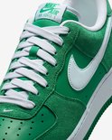 Detail van de groene Nike Air Force 1 sneaker: witte veters, groene suède en gladde leren overlays, en wit Nike logo.