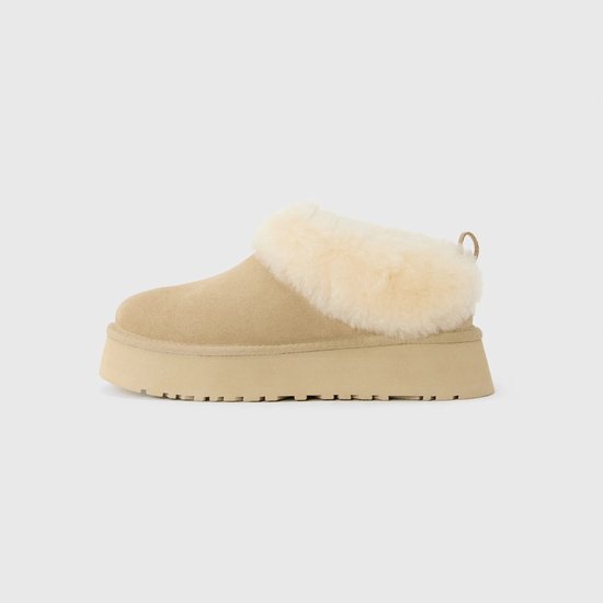 Beige suède pantoffel met dikke, crèmekleurige schapenvacht voering en plateauzool.
