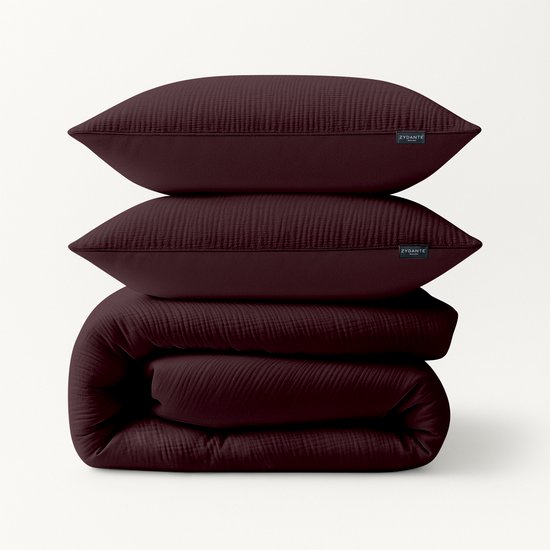 Pile de deux taies d'oreiller bordeaux et d'une couette, toutes avec une texture froissée.