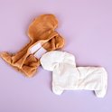 Bruin pluche teckel hoes met klittenband, naast een crèmekleurig kersenpitkussen.