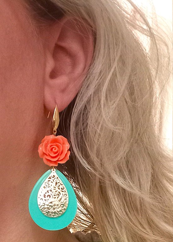 Model met oorbellen met koraaloranje roosjes en turkooise druppels met gouden filigraan.