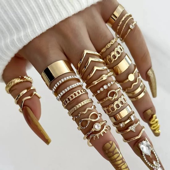 Gouden ringen gedragen op een hand met lange, goudkleurige nagels. Designs variëren van glad tot complex met steentjes.
