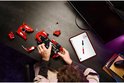 Een rode LEGO Technic Ferrari FXX K modelauto wordt op een bureau gebouwd, met een tablet die de instructies toont.