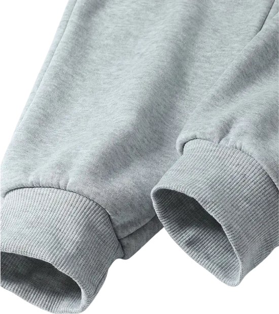 Detail van de geribde manchetten van een grijze joggingbroek.