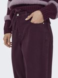 Close-up van een model met paarse wijde broek, met trekkoord en strik. Draagt een gestreepte trui.