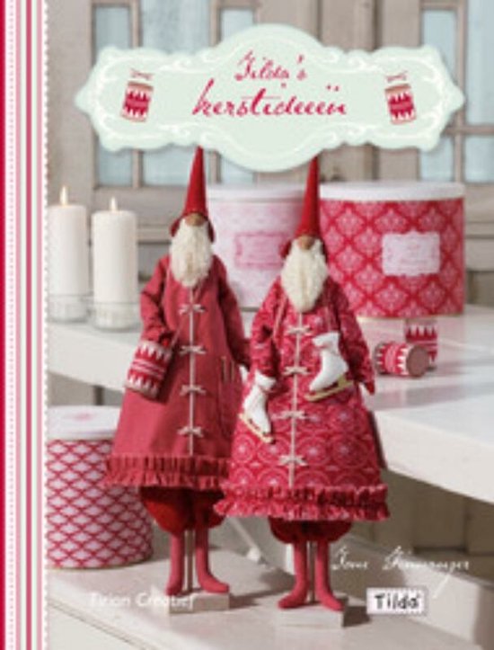 Twee kerstmannen in rode jassen, een met schaatsen, zittend op een tafel met kaarsen en decoratie.