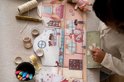 Meisje plakt stickers op een kartonnen speelset met kamers, meubels en figuren.