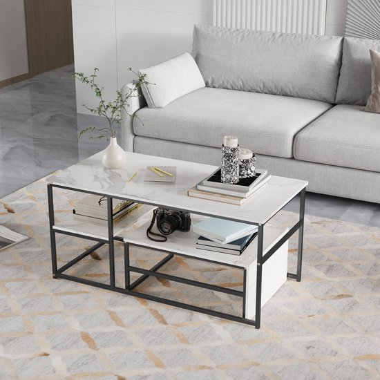 Table basse avec plateau aspect marbre, deux niveaux et cadre noir, dans un salon.