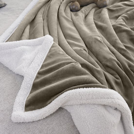 Gedetailleerd zicht op de taupe fleece stof en de witte, donzige sherpavoring van een plaid.