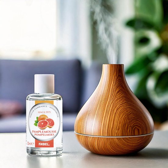 Flesje Pamplemousse parfum naast een houten luchtbevochtiger die stoom verspreidt.