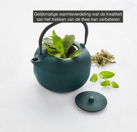 Donkergroene gietijzeren theepot met geribbelde textuur, gevuld met verse munt en gedroogde kruiden, met twee zwarte kopjes ernaast.
