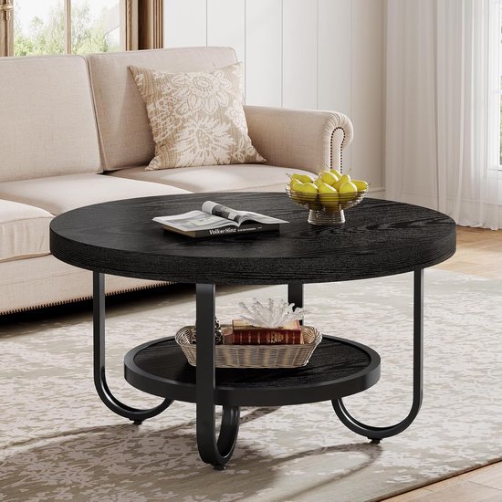 Zwarte ronde salontafel met een opbergplank, met een boek en een mandje met decoratie erop.