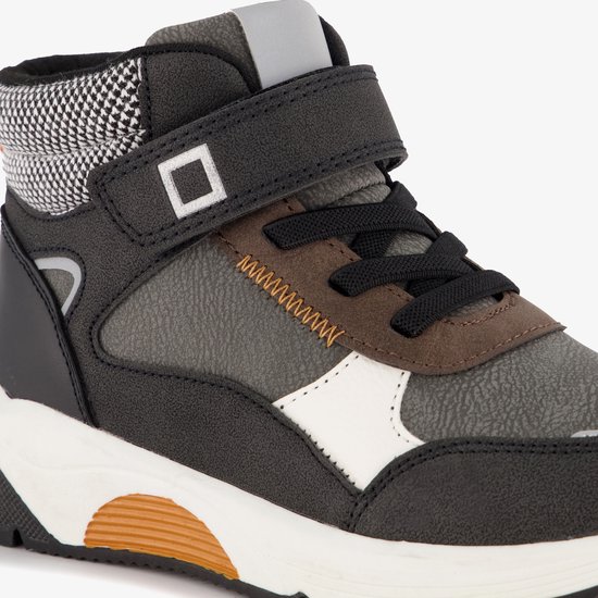Detail van blauwe doos hoge jongens sneaker in zwart en grijs met oranje zigzag stiksels.
