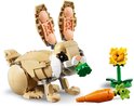 Lapin LEGO mange des feuilles vertes de carotte, avec fleur, fond blanc.