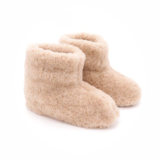 Hoge beige wollen sloffen met bruine zolen, van de zijkant gezien.