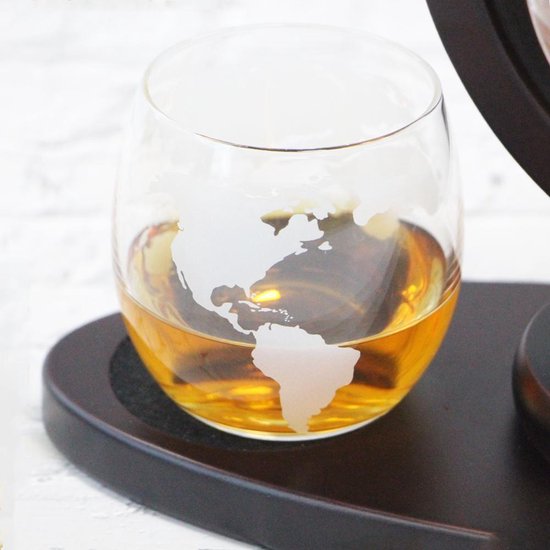 Glazen wereldbol karafglas met amberkleurige drank en opdruk wereldkaart.
