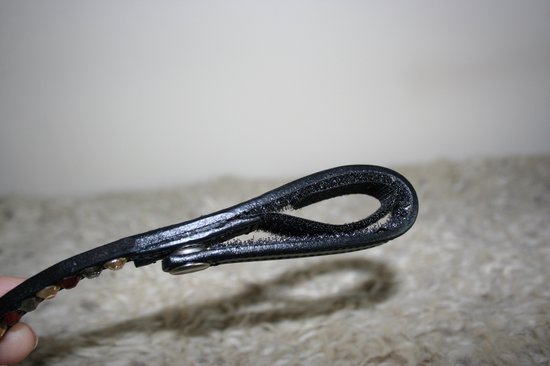 Détail de la boucle en cuir noir à l'extrémité du frontal, avec couture visible.