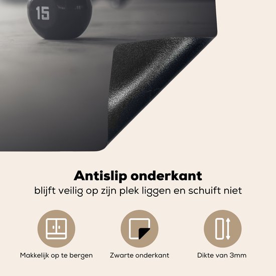 KitchenYeah® Inductie beschermer 76x51.5 cm - Verschillende kettlebellgewichten op de vloer in een fitnessruimte - Kookplaataccessoires - Afdekplaat voor kookplaat - Inductiebeschermer - Inductiemat - Inductieplaat mat