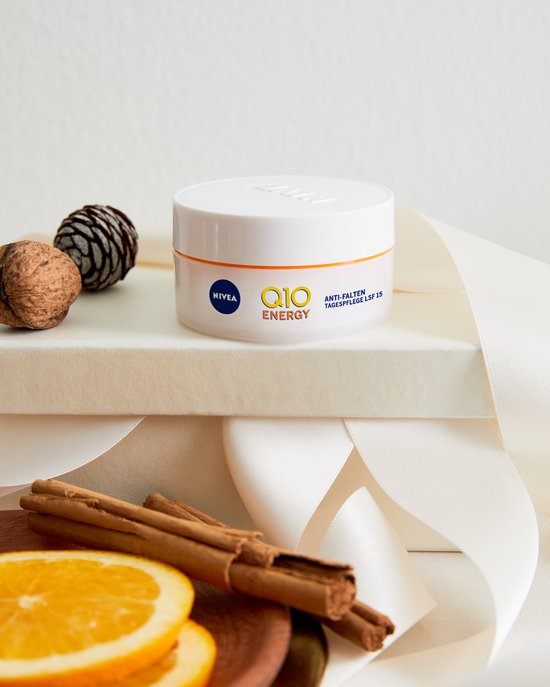 Nivea Q10 Energy anti-rimpel dagcrème potje met kaneelstokjes, walnoten en sinaasappelschijfjes.