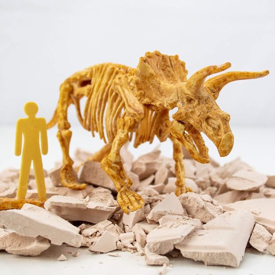 Gele dinosaurus skelet op brokstukken, naast een kleine gele menselijke figuur.
