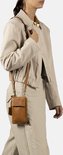 Model met cognac telefoonportemonnee gedragen als crossbody tas, met beige jas en broek.