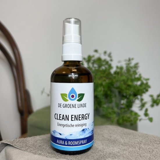 Bruine glazen sprayfles 'CLEAN ENERGY' staat op een doek, met op de achtergrond een stoel en plant.