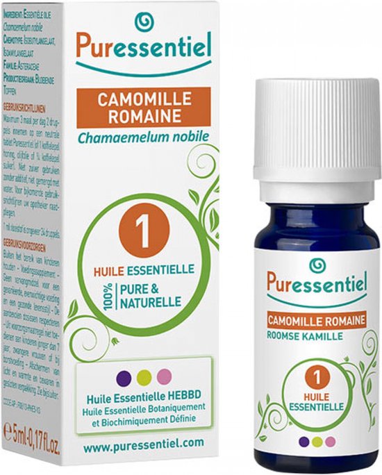 Flesje Puressentiel Roomse Kamille etherische olie in donkerblauw glas, met groene plantendecoratie.