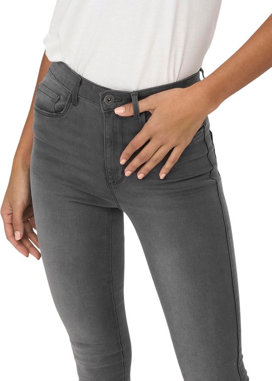 Detail van de voorkant van een grijze skinny jeans, gedragen door een model.