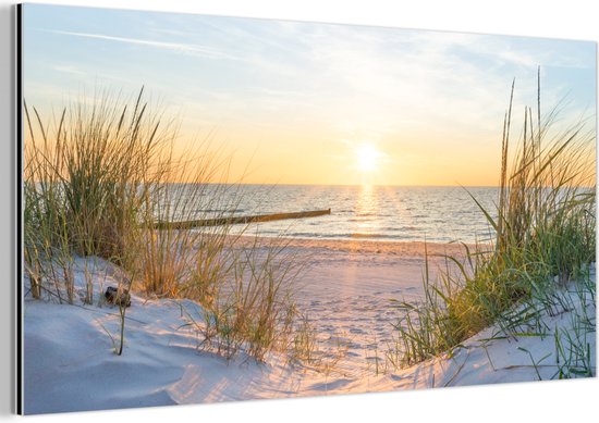Lever de soleil sur la plage avec des dunes, de l'herbe et des vagues douces.