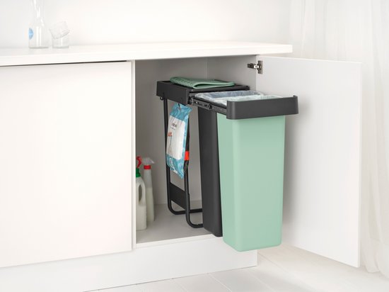 Mintgroene en donkergrijze Brabantia prullenbakken, in elkaar geschoven in een keukenkastje.