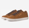 Een paar bruine leren Jack & Jones sneakers met veters en witte zolen, getoond op een grijze achtergrond.
