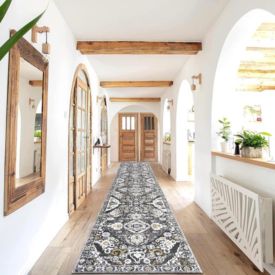 Un long tapis de couloir gris avec un motif classique noir, blanc et or, dans un couloir avec plancher en bois, portes et poutres.