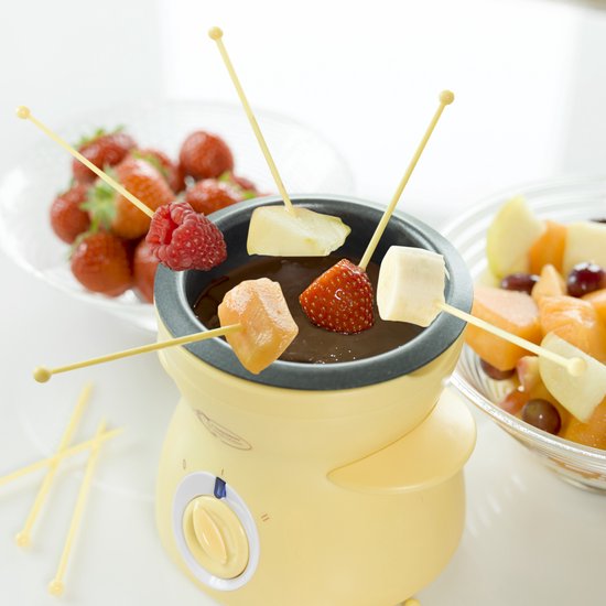 Gele chocoladefontein met fruit en marshmallows op prikkers.