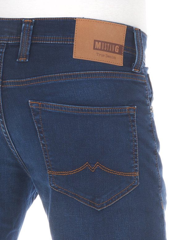 Achterkant van donkerblauwe jeans met een bruin leren 'Mustang True Denim' label.