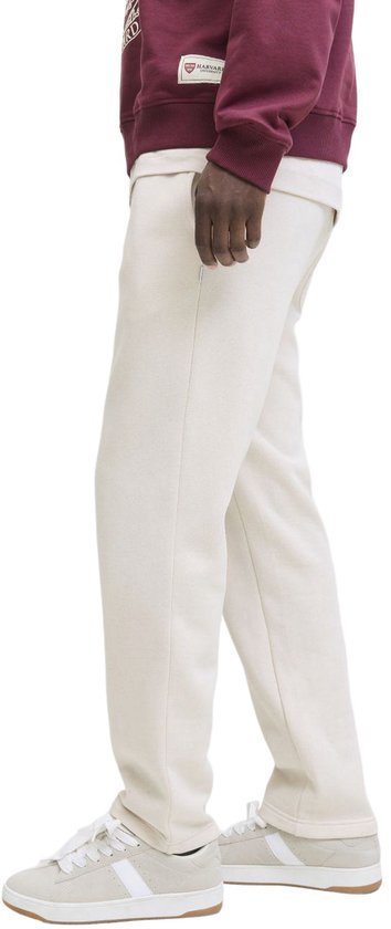 Man met crème joggingbroek en witte sneakers met strepen.