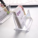 Transparante visitekaarthouder gevuld met visitekaartjes met een paars logo, op een bureau bij een toetsenbord.