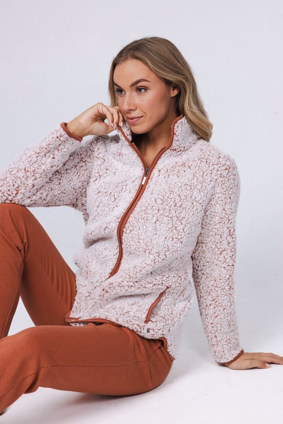 Vrouw in een lichtroze teddy fleece trui met bruine rits en broek.